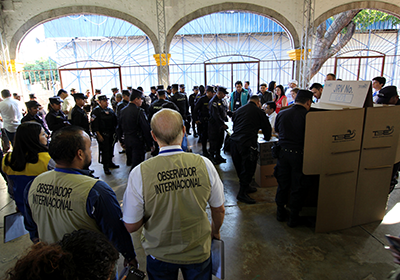 International observers watch police officers vote in a polling station.