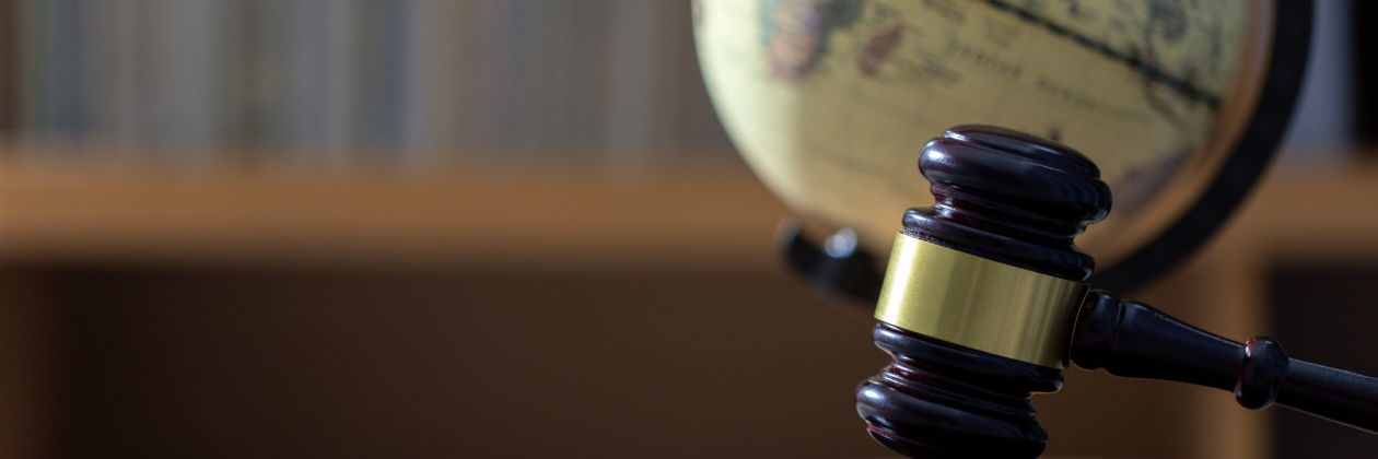 a gavel placed in front of a globe in a study. 