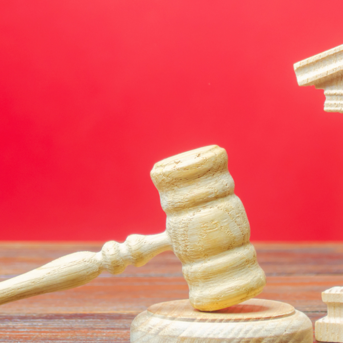 red background, wooden toy structure of a government building, wooden toy gavel. 
