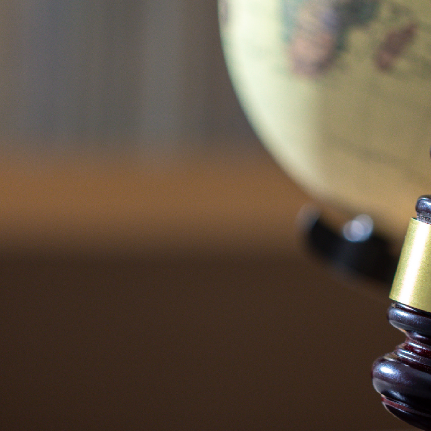 a gavel placed in front of a globe in a study. 