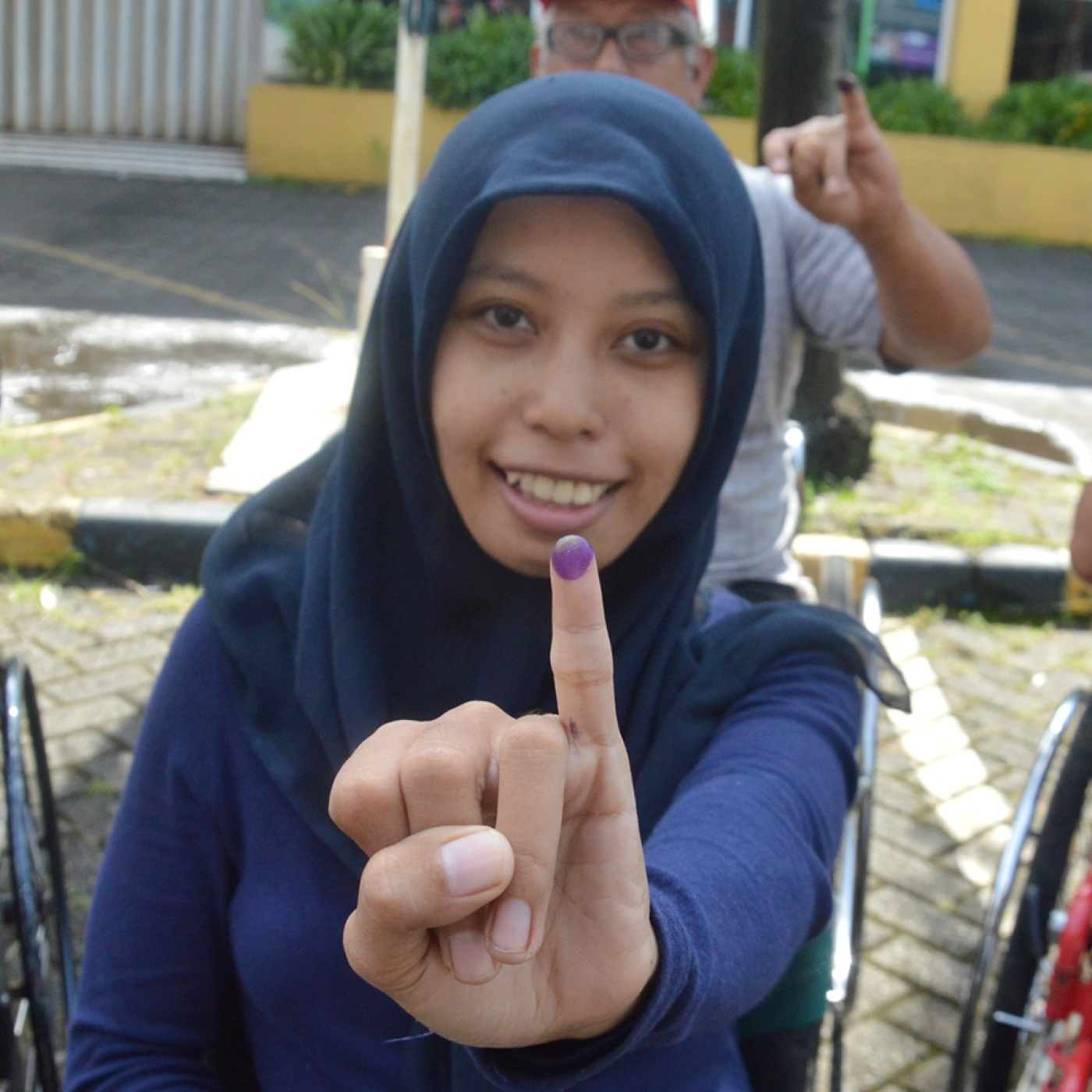 Indonesians with disabilities exercising their voting rights and showing inked fingers