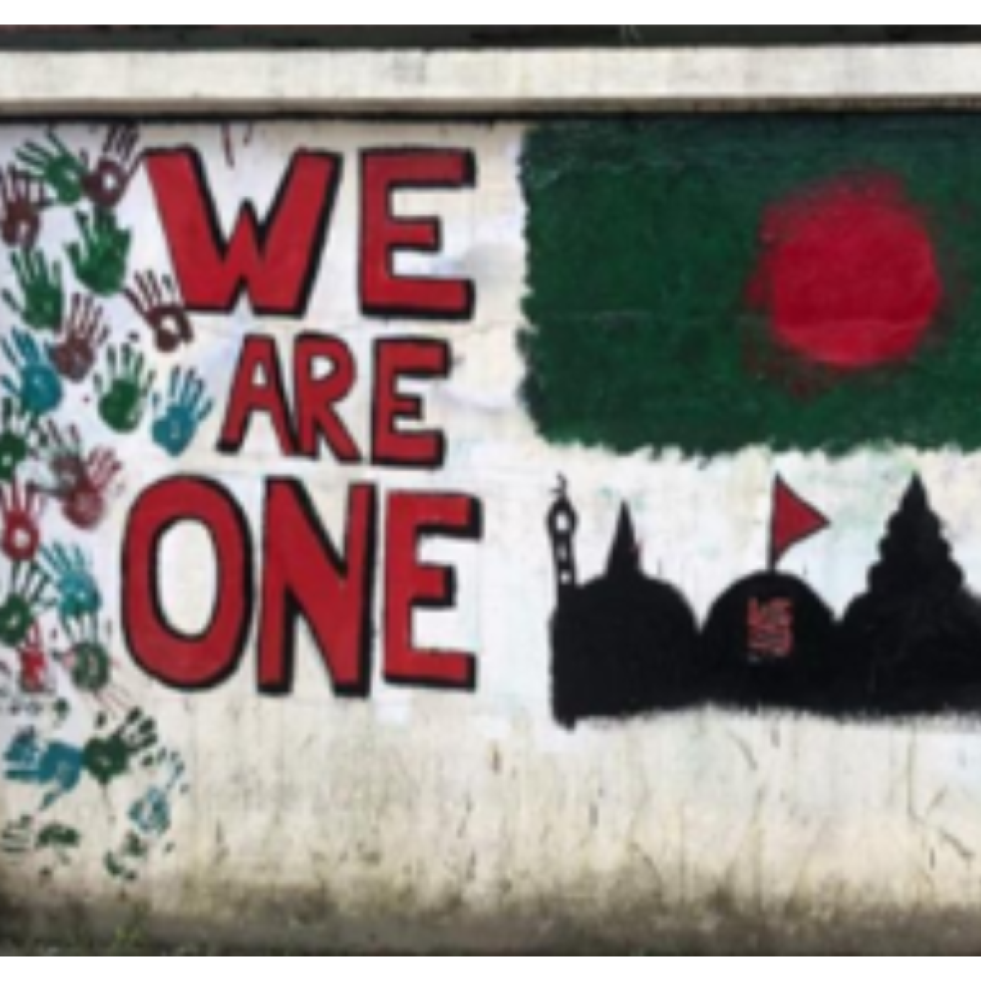 Mural with the phrase 'WE ARE ONE' painted in large letters, surrounded by handprints in various colors. Below the text, a silhouette skyline featuring a mosque, a temple, and a church, set against a red circle backdrop, symbolizing unity and diversity.