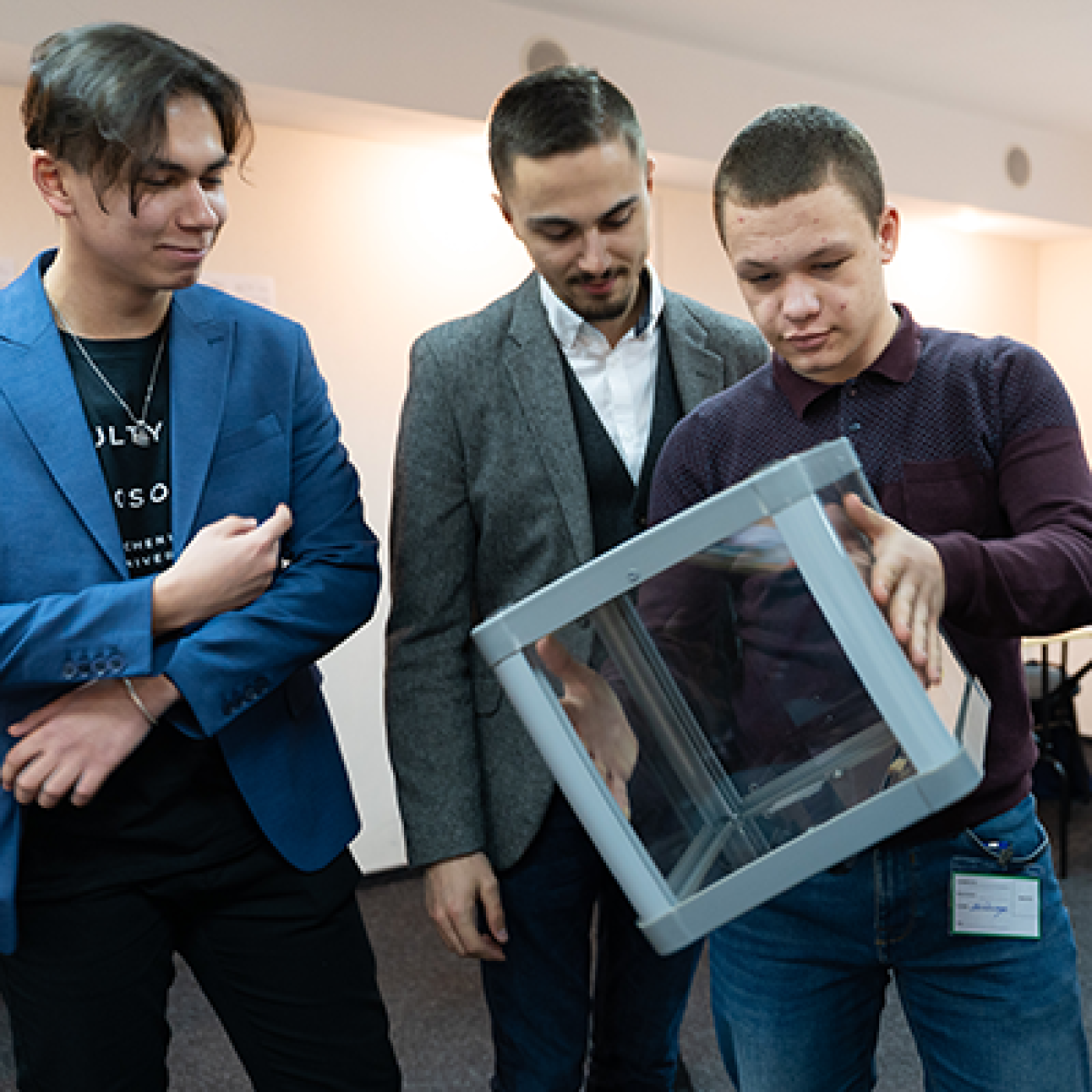 Three students examine a transparent cube.