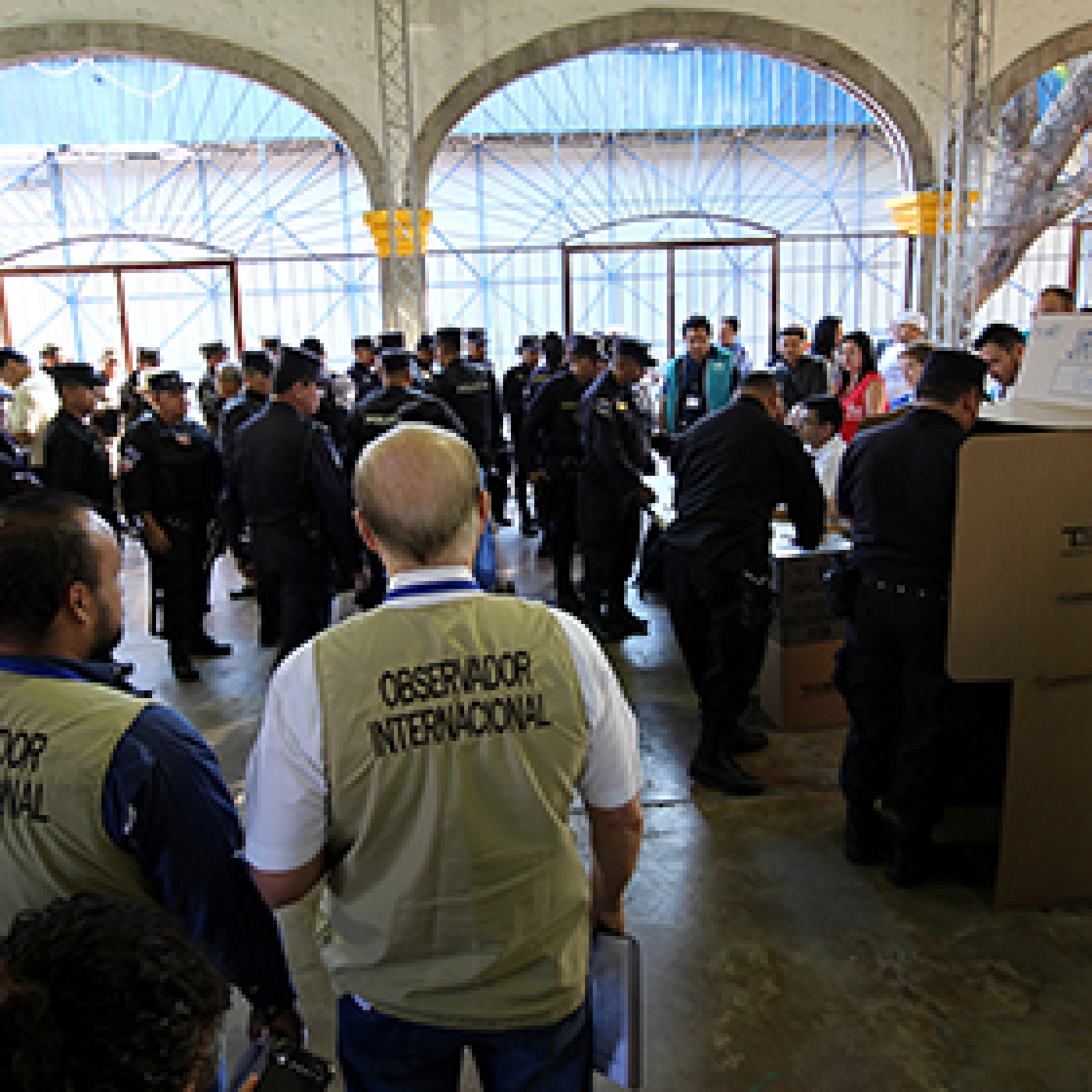 International observers watch police officers vote in a polling station.