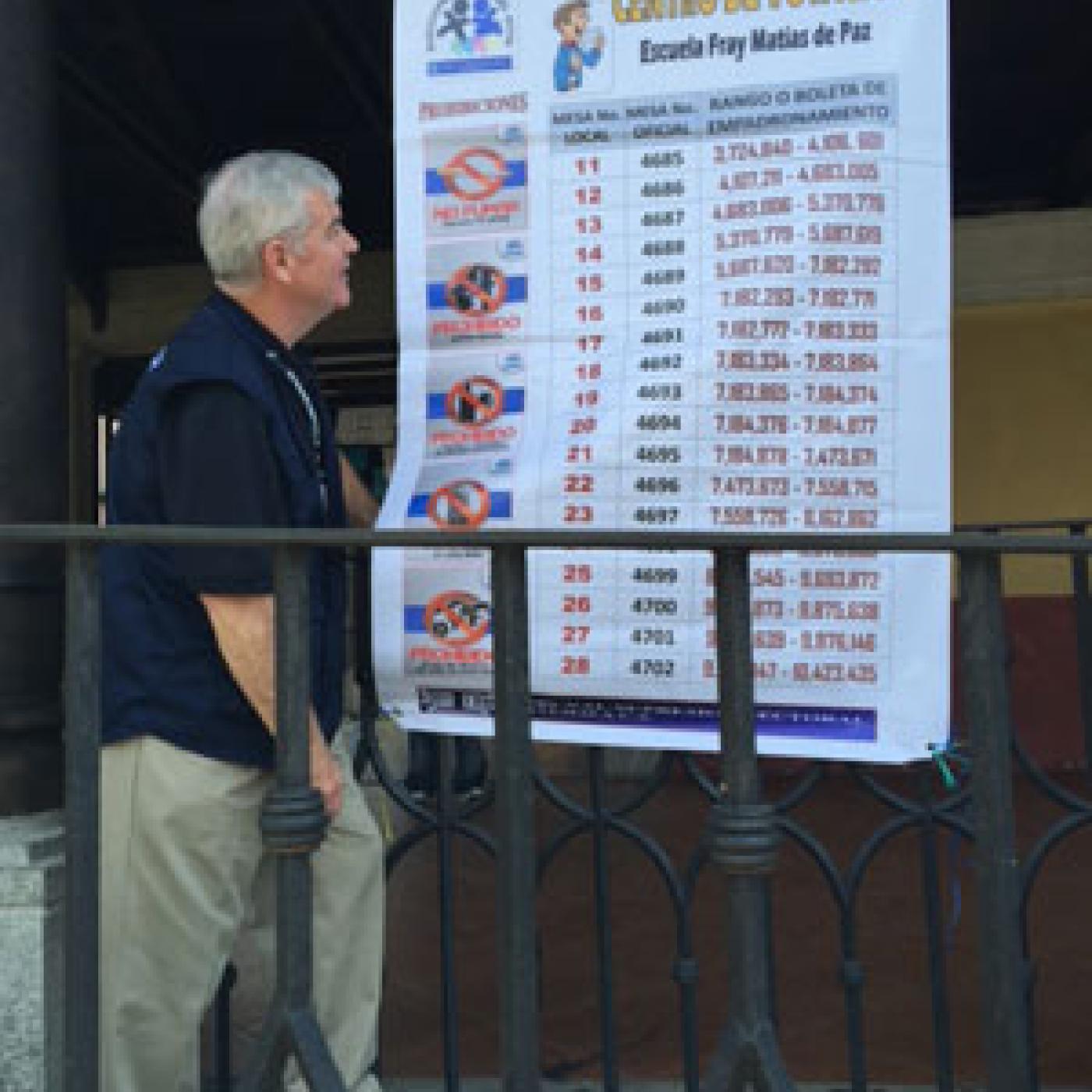 President Sweeney examines a voter education poster detailing how voters' can find their polling location in Ciudad Vieja.
