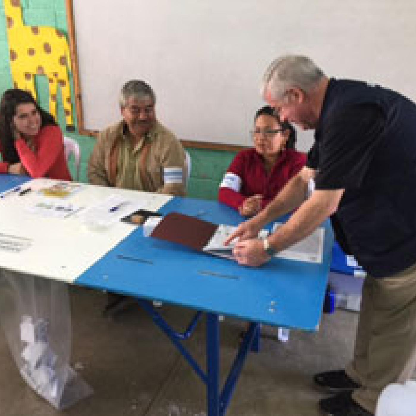 President Sweeney reviews the voter list with polling station workers in the city of Antigua.
